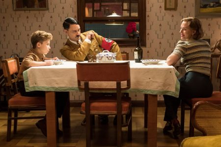 First still from the set of WW2 satire, Jojo Rabbit: Jojo (played by Roman Griffin Davis) having dinner with his imaginary friend Adolf (played by writer/director Taika Waititi), and his mother, Rosie (Scarlett Johansson  | Photo by Kimberley French, © Fox Searchlight